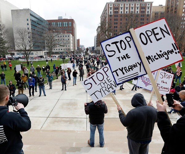 protesters in lansing hold up signs