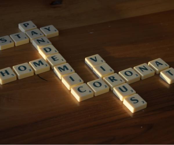 scrabble letters spell out stay at home a coronavirus