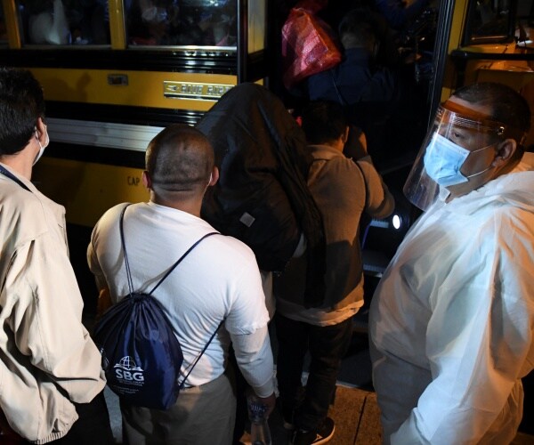 migrants wearing white shirts and face masks board a bus in guatemala city