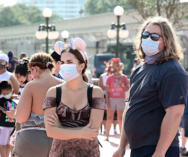 Guests wearing protective masks Saturday wait outside the Magic Kingdom theme park on first day of reopening