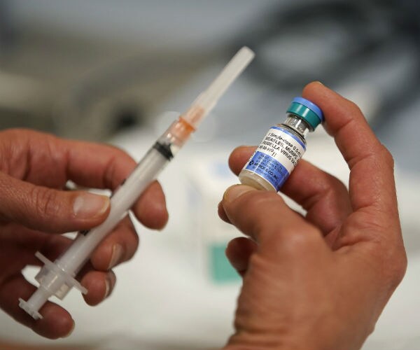 hands holding a syringe and a vial of the measles mumps and rubella vaccine