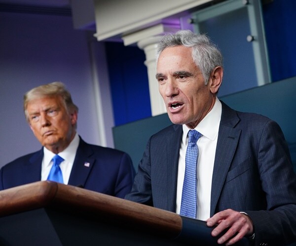 dr. scott atlas stands at a podium in front of a flag and next to donald trump