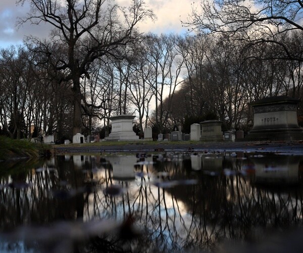 cemetary with tomb stones on the bank of a river or lake