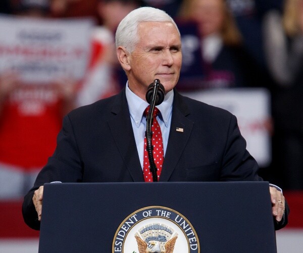 pence in a suit and red polka dotted tie speaks at a campaign rally
