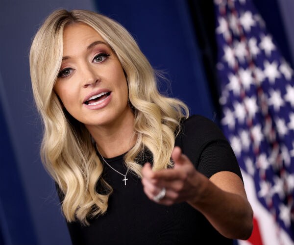 kayleigh mcenany is shown doing a press conference with the american flag in the background