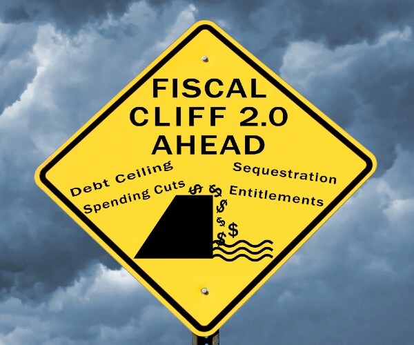 a yield sign with fiscal cliff ahead written on it