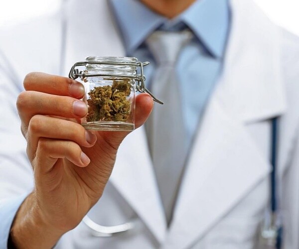 doctor holding up a glass container of cannabis