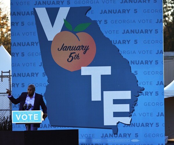 raphael warnock speaks onstage at rally