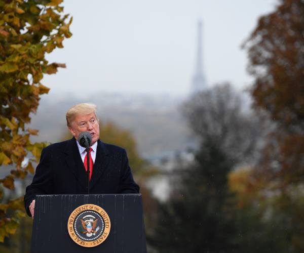 trump standing in the rain making a speech with the eiffel tower in the background