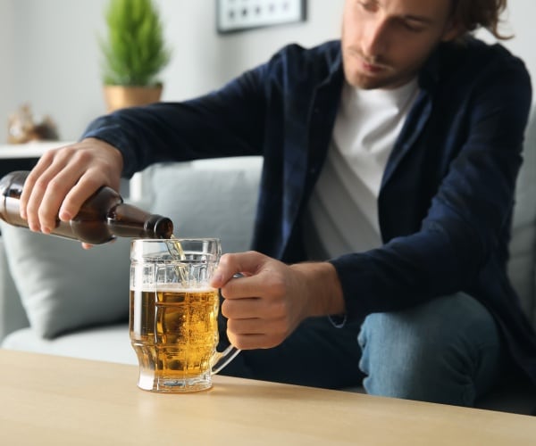 man pouring a beer in big glass mug