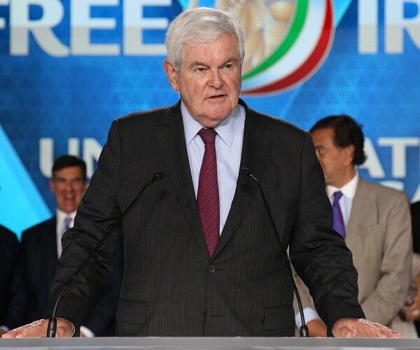 newt gingrich stands behind podium
