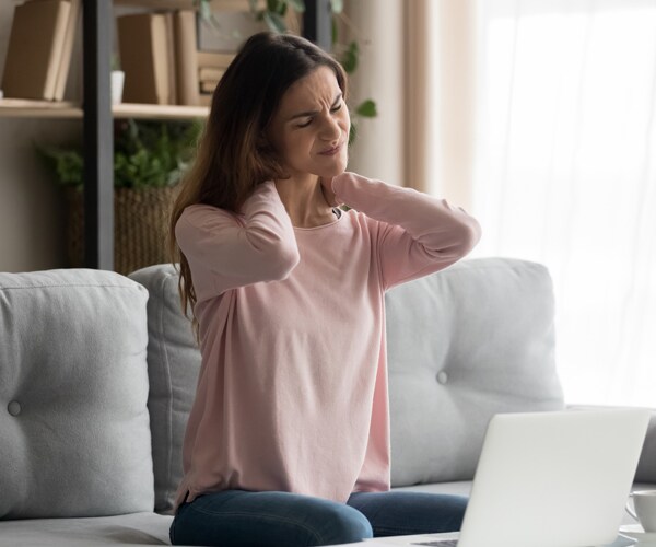 a woman having neck pain working on a computer