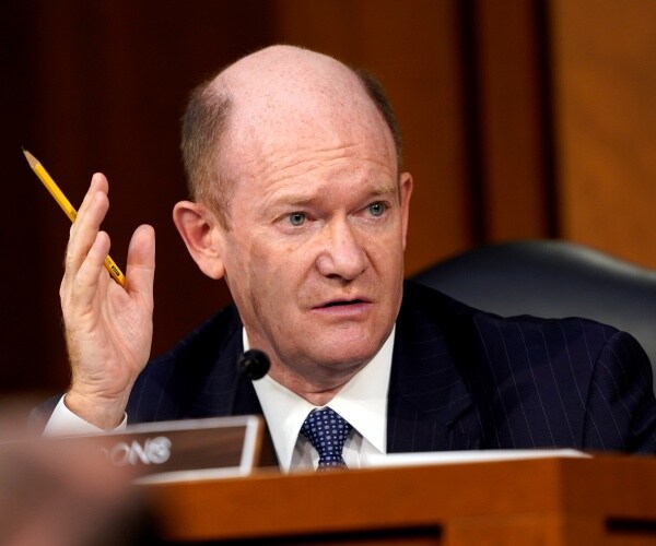 coons in a black suit holding up a pencil