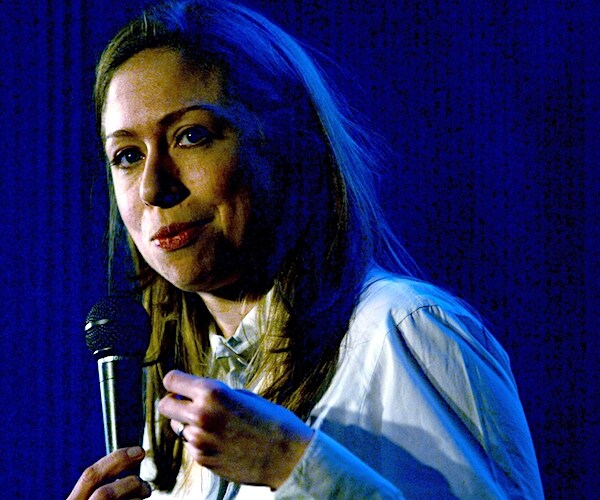 chelsea clinton holds a mic during a speech to a crowd