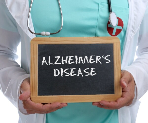 doctor holding chalkboard that says "Alzheimer's Disease"