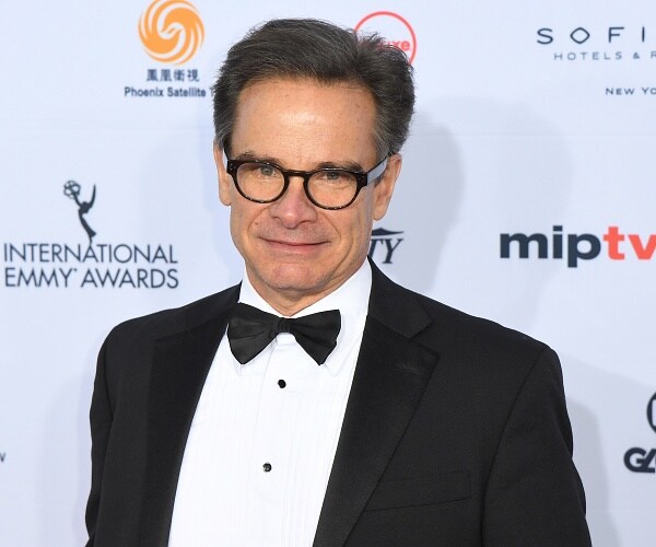 peter scolari stands on red carpet