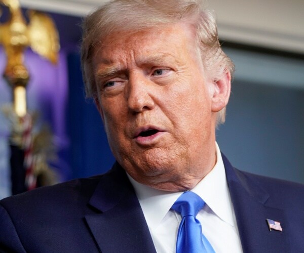 trump in a suit and blue tie in the press briefing room