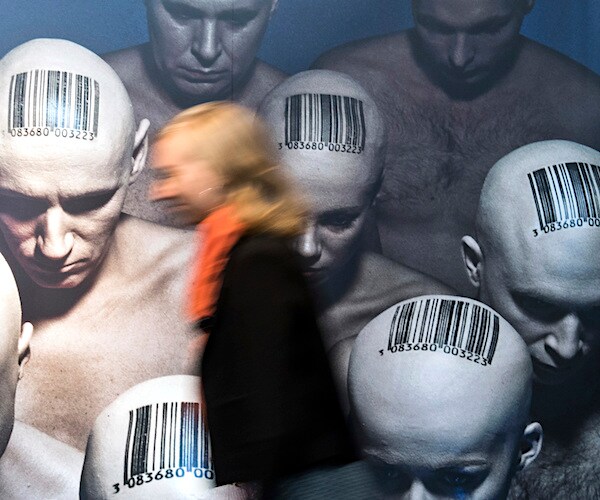 bald, nude men have black bar codes on the top of their heads to depict a census in counting people