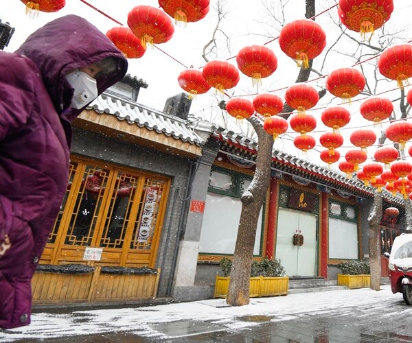 a person walks past shuttered shops in beijing
