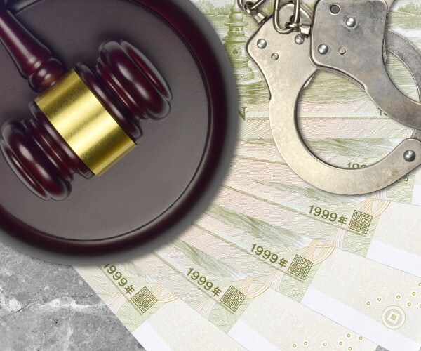 Chinese yuan bills and gavel with police handcuffs on court desk
