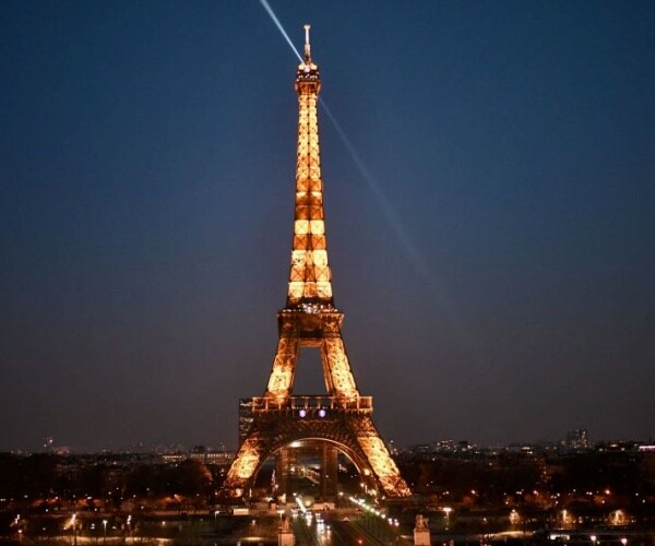 a beam shines from the eiffel tower at night