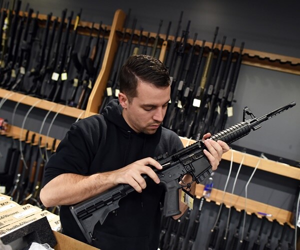 a man check the chamber of an assault-style rifle at a shooting range