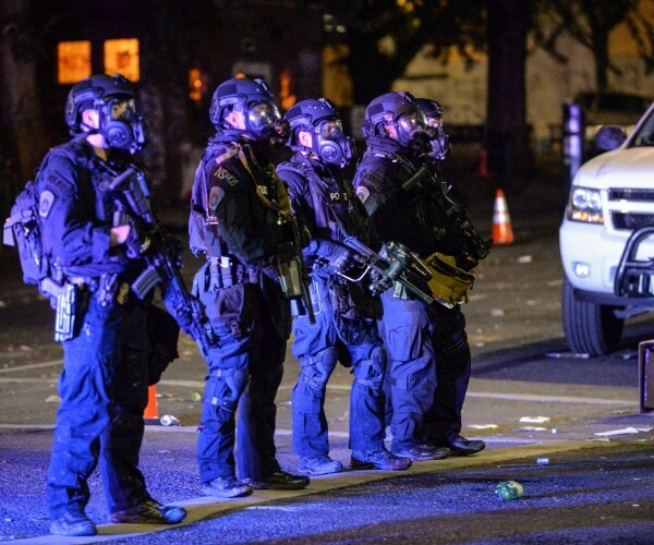 federal agents stand in a line in black uniforms in the middle of the night