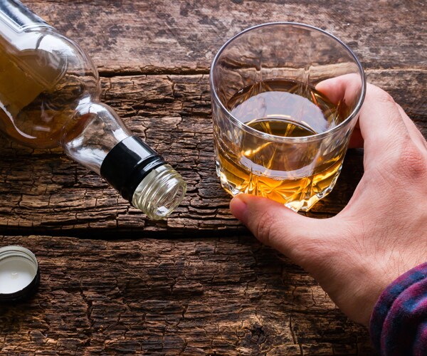 a man drinking next to an empty bottle