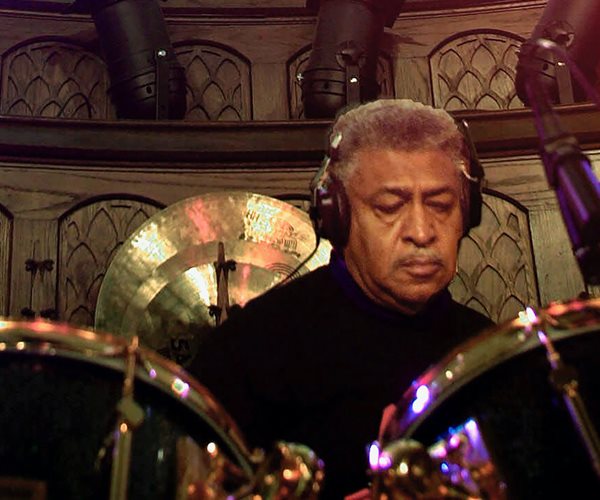 sam lay sits behind a drum kit with eyes downcast