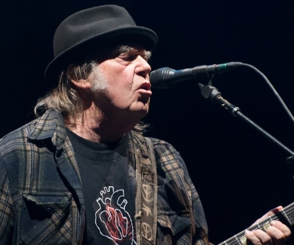 young in a black t shirt with a flannel shirt and black hat