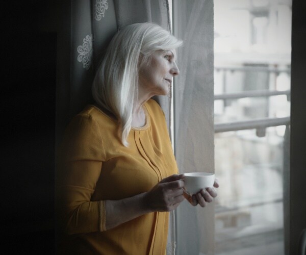 sad older woman looking out window