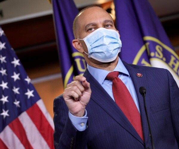 jeffries in a suit and red tie wearing a face mask
