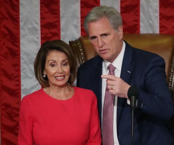 mccarthy in a navy blue suit and pink tie points to pelosi in a bright red dress