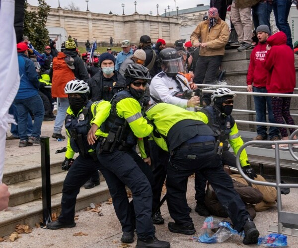 police arrest a protester as many others mill about.