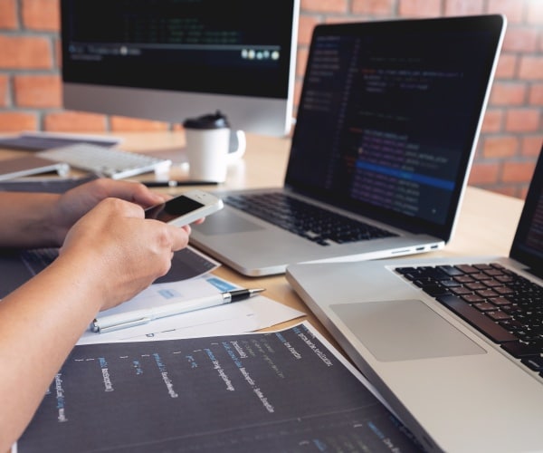 person working at desk with three computers/AI systems