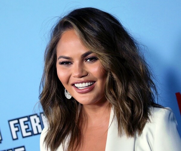 chrissy teigen stands on red carpet