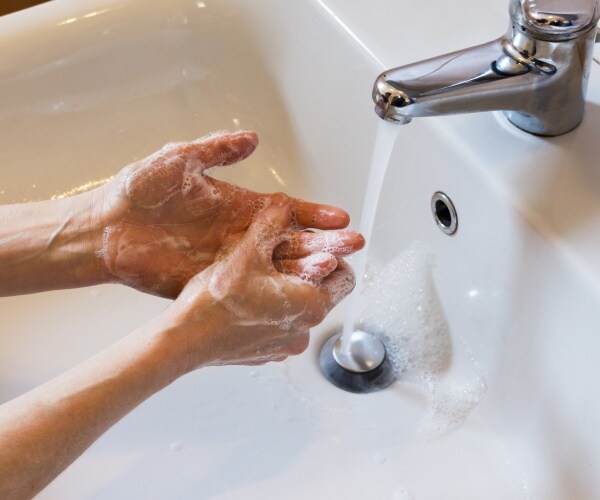 hand washing with soap at a sink with running water
