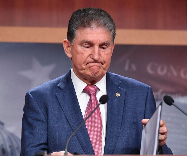 joe manchin looks down at podium