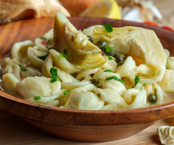 orecchiette pasta in a wooden bowl with capers and artichoke hearts