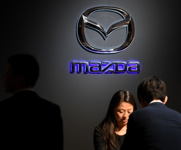mazda logo is shown with a man talking to the reception desk