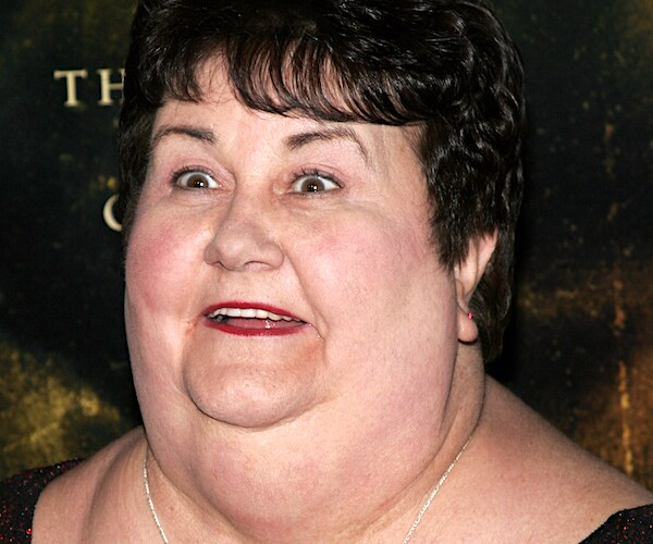 kathy lamkin stands wide eye on the red carpet of a premiere