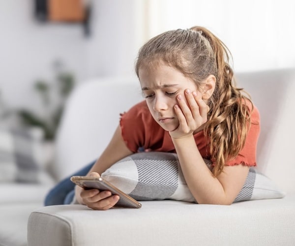 young girl looking said while scrolling on smartphone