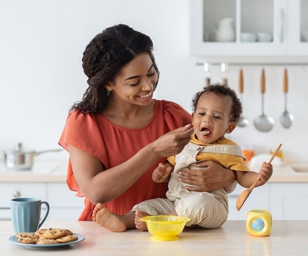 mom feeding baby with food in a bowl