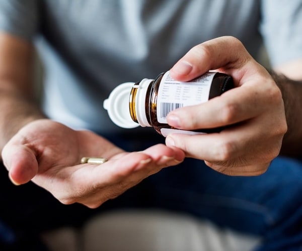 person getting vitamins from the bottle