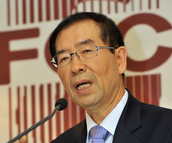 seoul mayor in a black suit and blue patterned tie speaking into a mic
