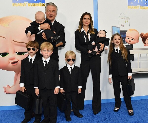 alec and hilaria baldwin stand on blue carpet with their six kids