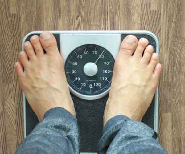 a barefoot white male standing on a scale