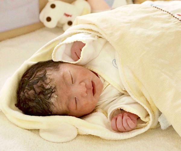 a sleeping baby lies wrapped up after being born