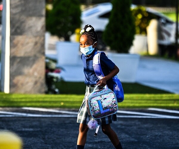 girl wears face mask as she walks into school