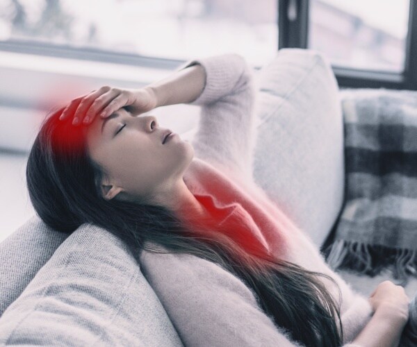 woman laying back on couch with headache and sore throat